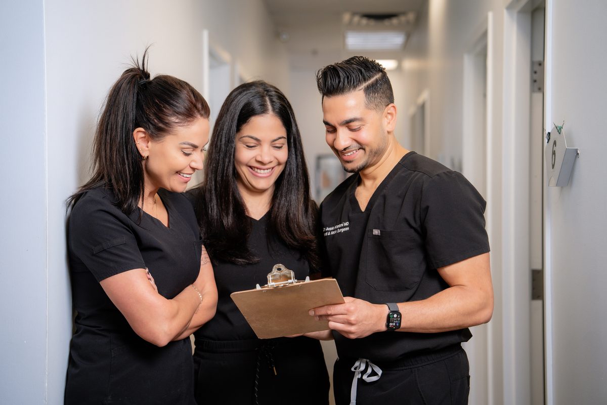 Dr. Justin Khetani reviewing notes on a clipboard with Brandi and Ana in the Burlington office