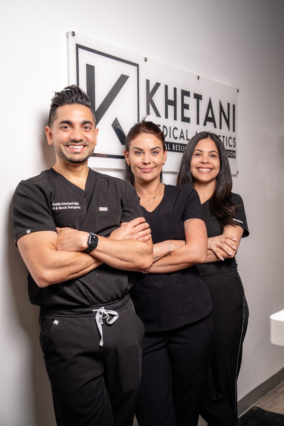Dr. Justin Khetani with the two members of the clinic team, standing beneath the practice sign in the Burlington office